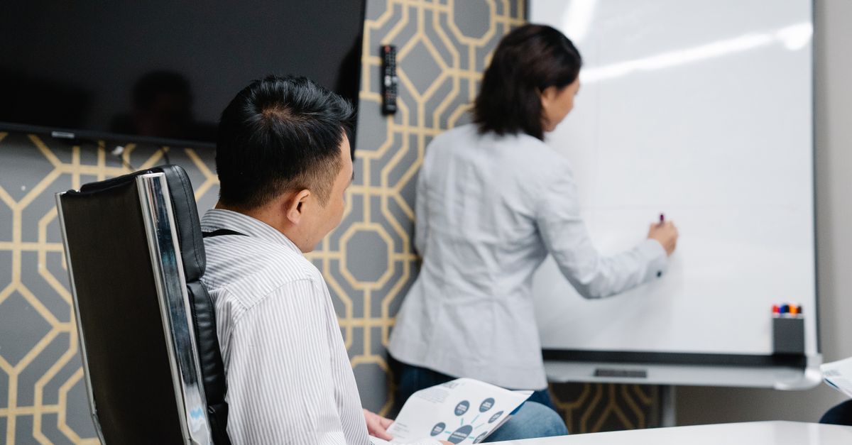 Business professionals engaging in a collaborative meeting using a whiteboard for brainstorming.