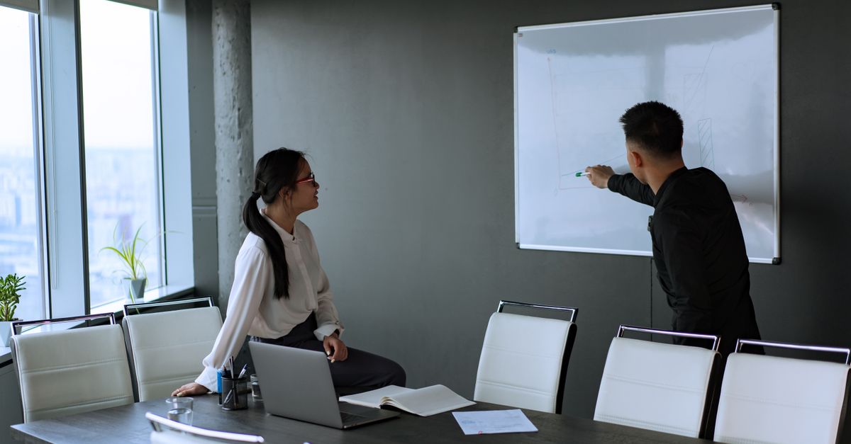 Colleagues engage in a productive office meeting with a whiteboard presentation.