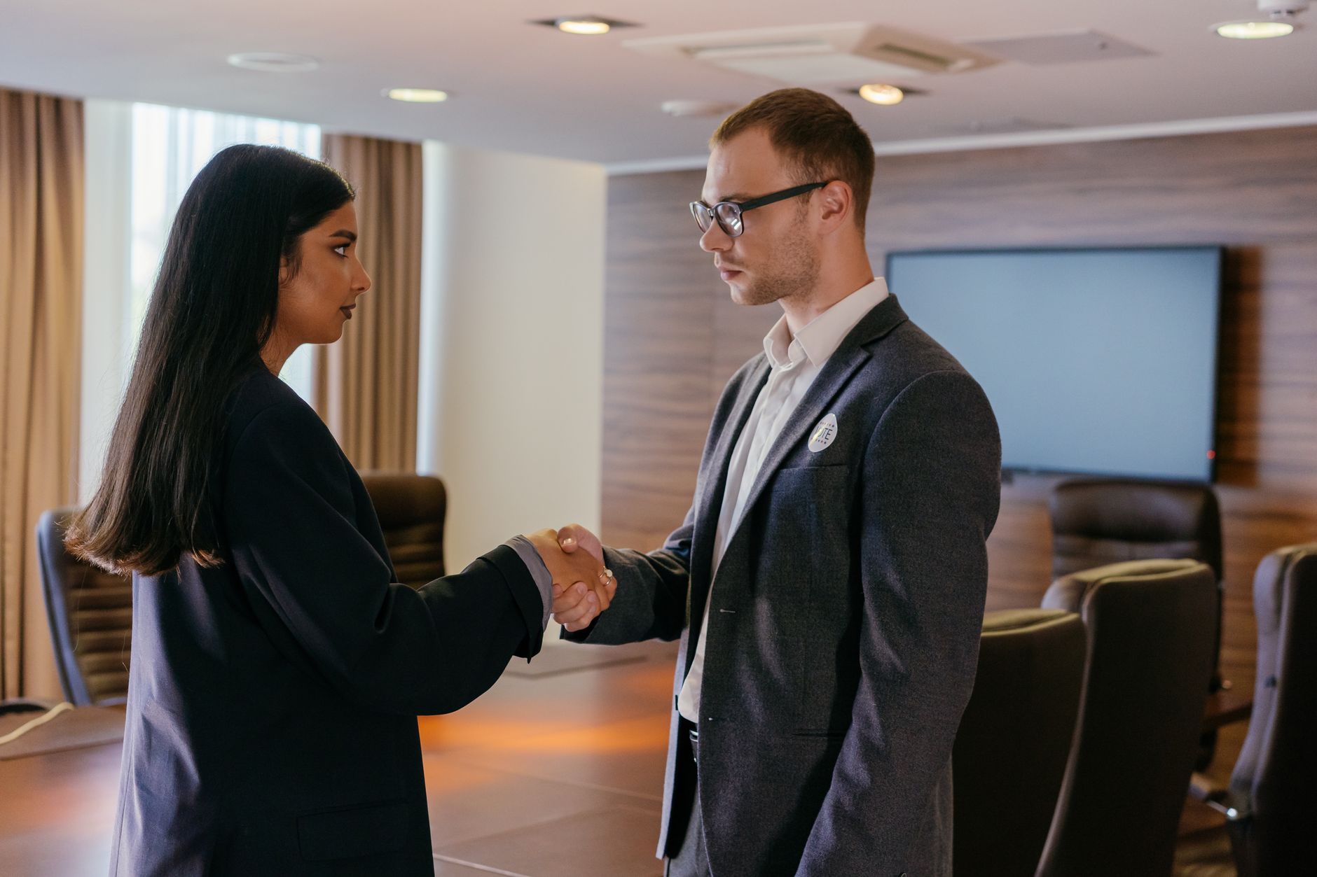 Two professionals shaking hands to seal a supplier agreement in a conference room